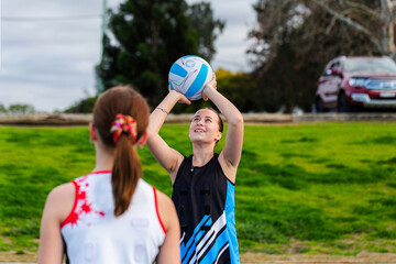 Aboriginal teenager playing netball game shooting for the goal