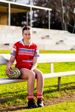 Portrait of young aboriginal teen footy player with football sitting on sidelines of playing field