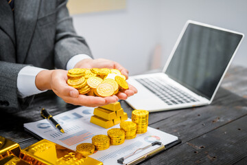 Businessman in suit sits at his desk, holding a shining gold bar. financial charts, the scene symbolizes wealth, investment success, growing influence of cryptocurrency and blockchain.