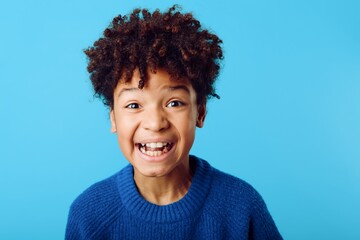 playful expression young african american boy making silly faces against a vibrant blue backdrop
