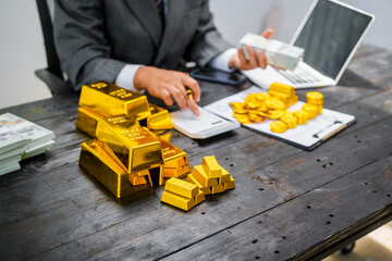Businessman in suit sits at his desk, holding a shining gold bar. financial charts, the scene...