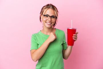 Young Russian woman holding a refreshment isolated on pink background celebrating a victory