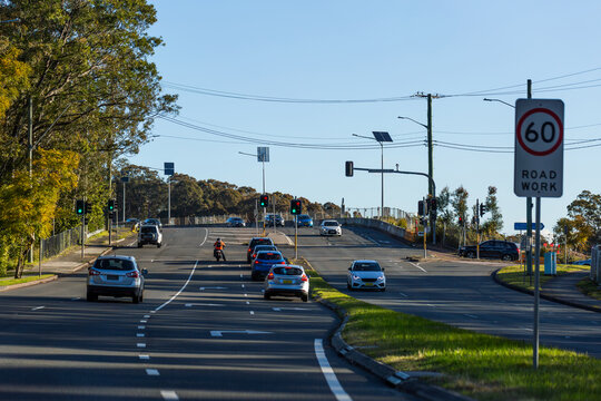 cars and motorcyclist at intersection with traffic light