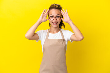 Restaurant waiter Russian girl isolated on yellow background with surprise expression