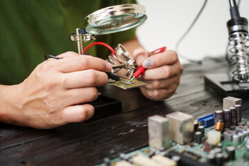 Technician carefully repairs a computer circuit board, using precision tools to address hardware...