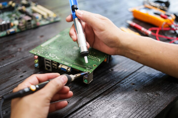 Technician carefully repairs a computer circuit board, using precision tools to address hardware...