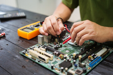 Technician carefully repairs a computer circuit board, using precision tools to address hardware...