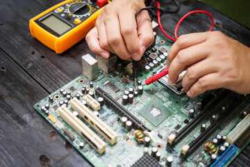 Technician carefully repairs a computer circuit board, using precision tools to address hardware...