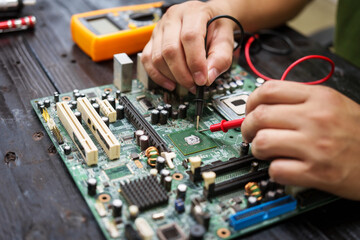 Technician carefully repairs a computer circuit board, using precision tools to address hardware...