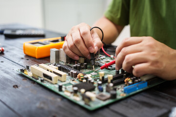 Technician carefully repairs a computer circuit board, using precision tools to address hardware issues. technical expertise needed for troubleshooting and upgrading electronic systems in workspace.