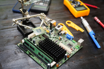 Technician carefully repairs a computer circuit board, using precision tools to address hardware issues. technical expertise needed for troubleshooting and upgrading electronic systems in workspace.