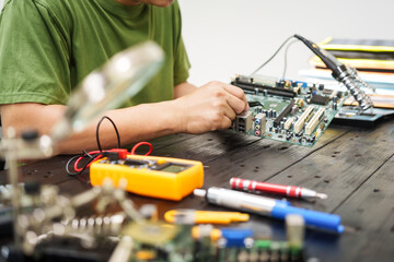 Technician carefully repairs a computer circuit board, using precision tools to address hardware issues. technical expertise needed for troubleshooting and upgrading electronic systems in workspace.