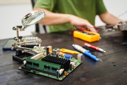 Technician carefully repairs a computer circuit board, using precision tools to address hardware issues. technical expertise needed for troubleshooting and upgrading electronic systems in workspace.