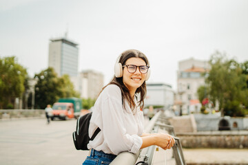 Young caucasian woman listening to music or audio book in the city	