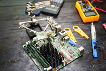 Technician carefully repairs a computer circuit board, using precision tools to address hardware...