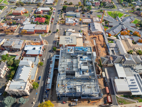 Aerial view of multi level construction site alongside existing city buildings