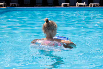 Child girl swims with an inflatable ring in the pool