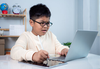 Little Asian boy student using computer laptop learning. Educational of tech concept, Staying at home, Presenting a modern educational way of life. Virtual internet online class from school teacher.