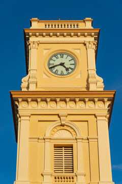 Looking up at an historic clock tower bathed in afternoon light