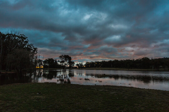 Dark cloudy night sky at sunset dusk reflecting on river water - Powered by Adobe