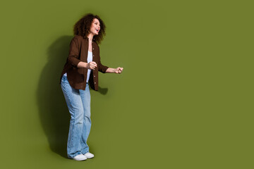 Full body portrait of nice young girl celebrate empty space ad isolated on khaki color background