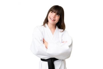 Little Caucasian girl doing karate over isolated background looking up while smiling