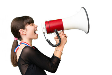 Naklejka premium Little caucasian girl with medals over isolated background shouting through a megaphone