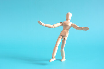 The concept of a cautious person who takes a step forward. A wooden doll takes a cautious step forward against a light background.