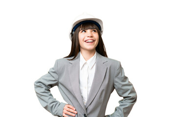 Little girl playing as a architect with helmet and holding blueprints over isolated background posing with arms at hip and smiling