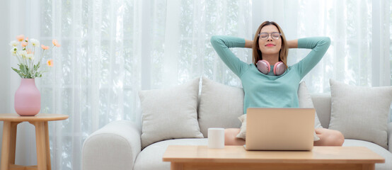 Young asian woman wearing glasses sitting on sofa for relax and leisure in living room at home, woman with cozy and resting in house, lifestyle and domestic life concept.