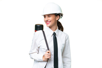 Young architect woman with helmet and holding blueprints over isolated background looking side