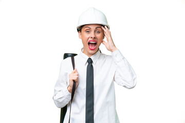 Young architect woman with helmet and holding blueprints over isolated background with surprise expression