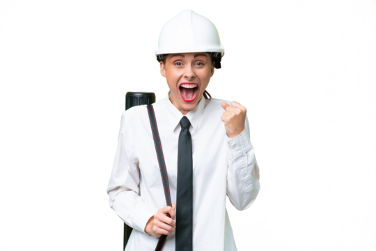 Young architect woman with helmet and holding blueprints over isolated background celebrating a victory in winner position