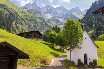 view of bavarian alps with chapel and old farmhouse in oberstdorf germany einödsbach