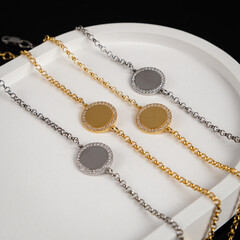 Jewelry for women. Gold and silver bracelets with a pendant on a black background. White stand for jewelry.