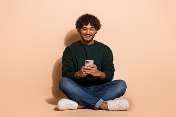 Full size photo of nice young man use smart phone wear sweater isolated on beige color background