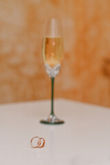 wedding rings on the background of a glass of champagne. vertical. selective focusing.