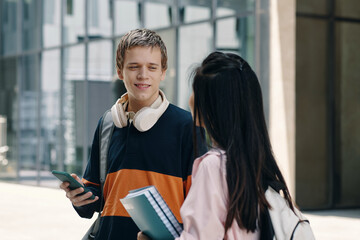 Boy talking to his classmate while they meeting outdoors after school