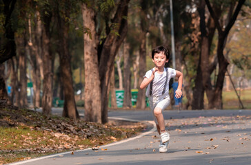 Young Asian boy running energetically down a tree-lined path in a park, capturing a playful and active moment outdoors. carefree expression reflects excitement and freedom to enjoy fresh air outdoor