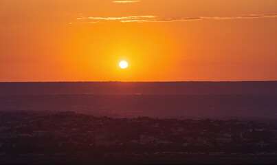 Fototapeta premium The sun sets behind the horizon, casting a warm glow over the city skyline