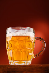 pouring beer into glass, wooden stand, red background, close-up view of object, beer foams and bubbles