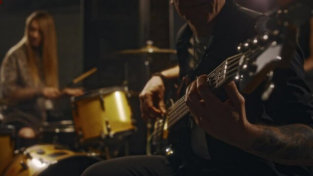 Medium shot of diverse music band mates spending time together in recording studio, playing percussions and electric guitars rehearsing while preparing for live performance