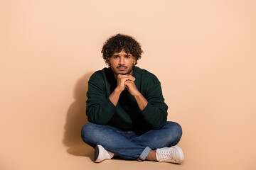 Full size photo of nice young man sit floor wear sweater isolated on beige color background