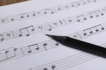 Sheet with musical notes and pencil, closeup view