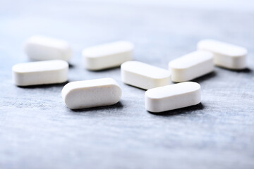 Amino acids tablets. Nutrition for bodybuilding. Fitness supplements on bright wooden background. Soft focus. Copy space.