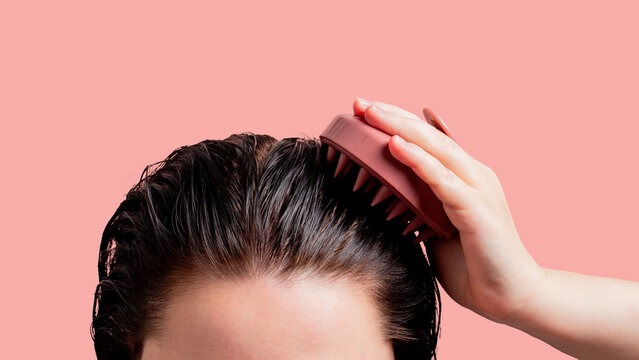 Woman doing scalp massage with pink massager. Part of the female head with on the pink background. Isoalted image. Mock up for design and banners