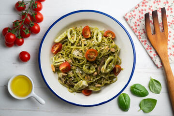 Italian noodles with pesto sauce and squid. Top view table with  decoration.