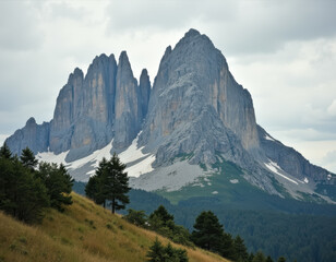 Obraz premium 木々や緑に囲まれ、頂上に雪が積もった高い岩山のグループ