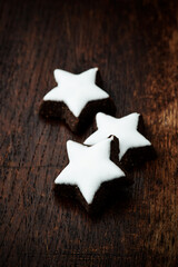 Christmas cookies (cinnamon stars) and brown sugar on dark background. Close up.