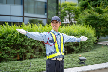 笛の合図で交通誘導をするガードマン男性 © rrice